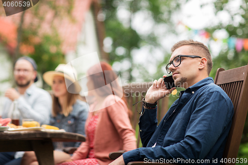 Image of man with smartphone and friends at summer party