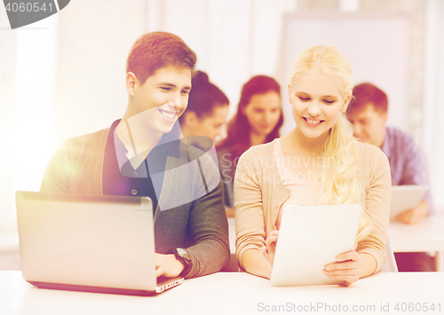 Image of two smiling students with laptop and tablet pc