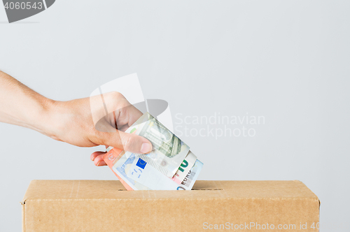 Image of man putting euro money into donation box