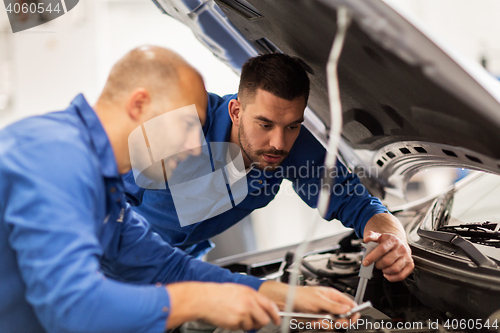 Image of mechanic men with wrench repairing car at workshop