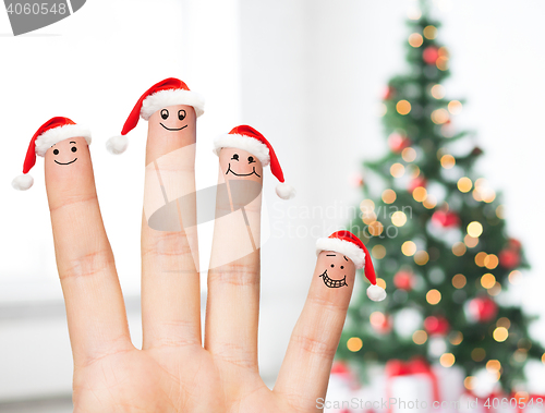 Image of close up of hand with four fingers in santa hats