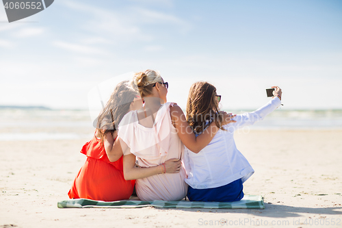 Image of happy women taking selfie by smartphone on beach