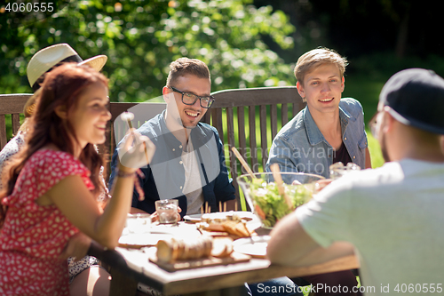 Image of happy friends having dinner at summer garden party