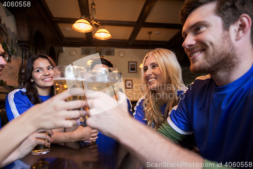 Image of football fans clinking beer glasses at sport bar