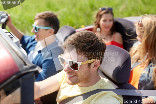 Image of happy friends driving in cabriolet car outdoors