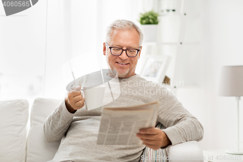 Image of senior man in glasses reading newspaper at home