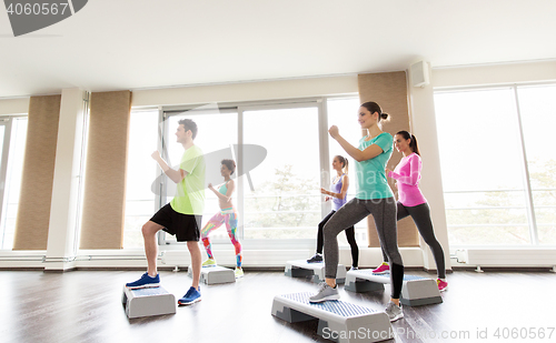 Image of group of people exercising on steppers in gym