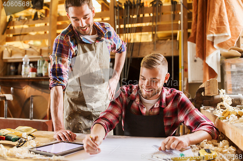 Image of workmen with tablet pc and blueprint at workshop