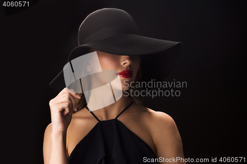 Image of beautiful woman in black hat over dark background