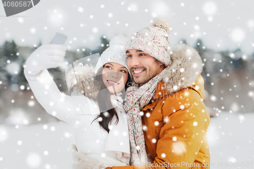 Image of happy couple taking selfie by smartphone in winter