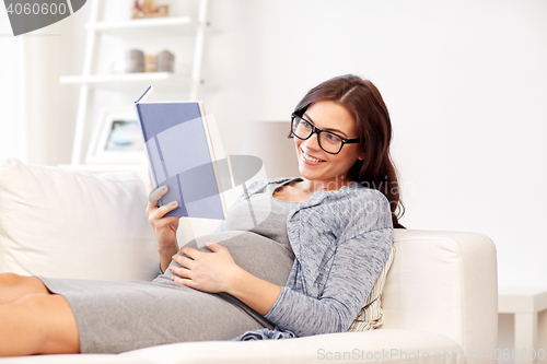 Image of happy pregnant woman reading book at home