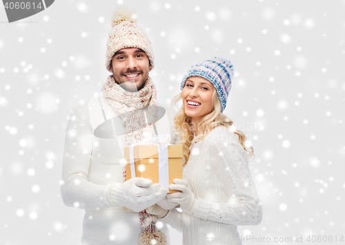 Image of smiling couple in winter clothes with gift box