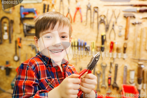 Image of happy little boy with pliers at workshop
