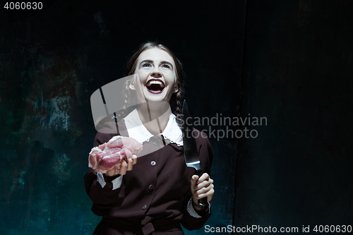 Image of Bloody Halloween theme: crazy girl with a knife and raw meat