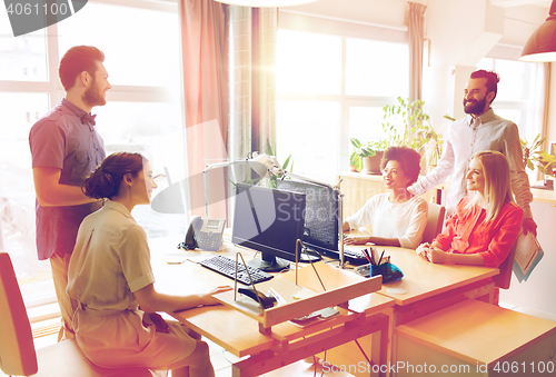 Image of happy creative team talking in office