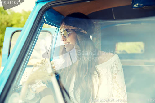 Image of smiling young hippie woman in minivan car