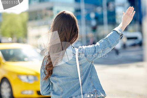Image of young woman or girl catching taxi on city street