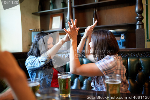 Image of happy friends with beer celebrating at bar or pub