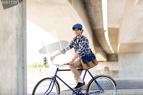 Image of happy hipster man with bag riding fixed gear bike