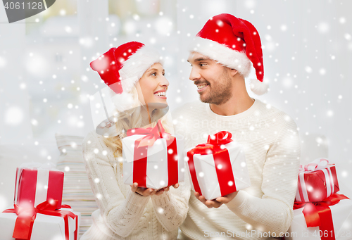 Image of happy couple at home exchanging christmas gifts