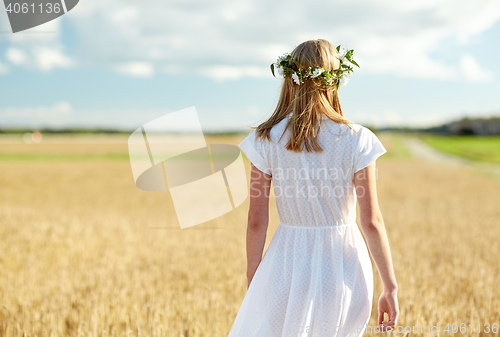 Image of happy young woman in flower wreath on cereal field