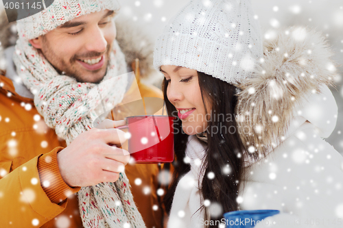 Image of happy couple with tea cups over winter landscape