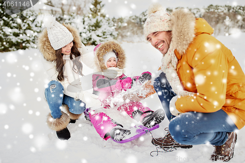 Image of happy family with kid on sled having fun outdoors