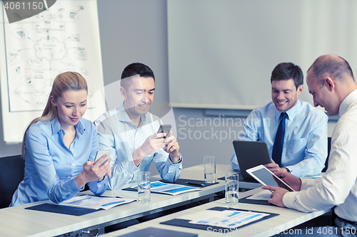Image of smiling business people with gadgets in office