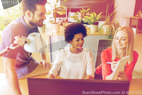 Image of happy creative team with computer in office