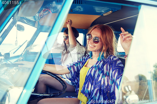 Image of smiling young hippie women driving minivan car