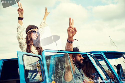 Image of hippie friends over minivan car showing peace sign