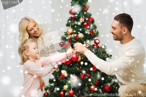 Image of happy family decorating christmas tree at home