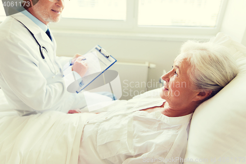 Image of senior woman and doctor with clipboard at hospital