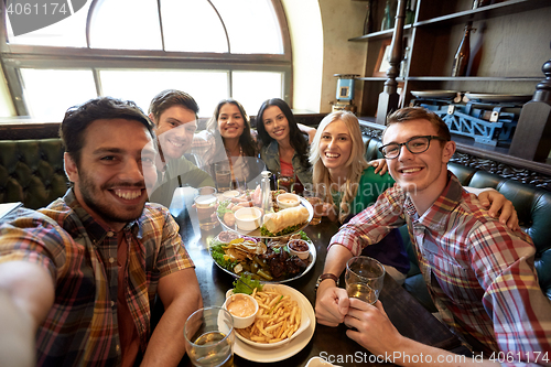 Image of happy friends taking selfie at bar or pub