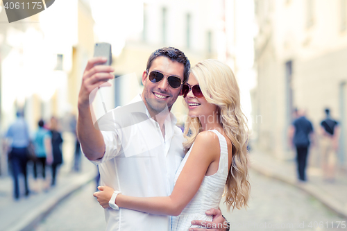 Image of smiling couple with smartphone in the city