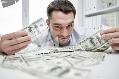 Image of happy businessman with heap of money in office