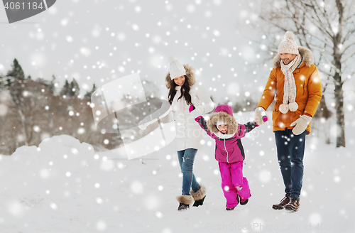 Image of happy family in winter clothes walking outdoors