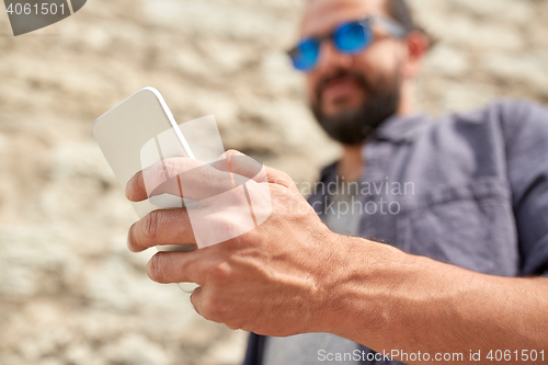 Image of close up of man with smartphone at stone wall