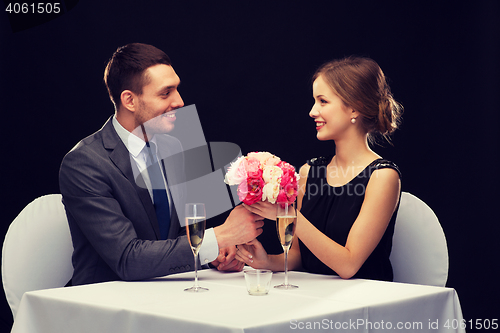 Image of smiling man giving flower bouquet to woman