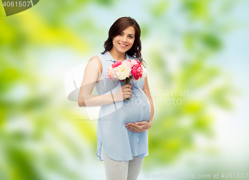 Image of happy pregnant woman with flowers touching belly