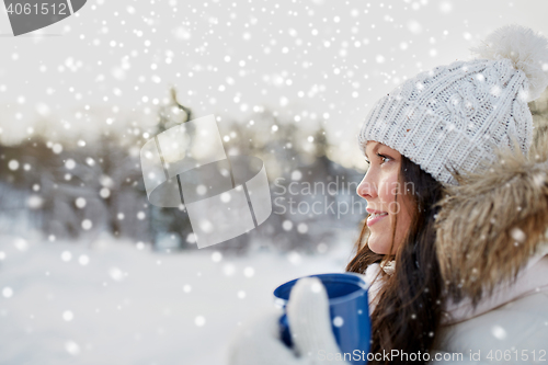 Image of happy young woman with tea cup outdoors in winter