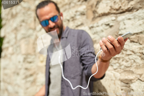 Image of man with earphones and smartphone on street