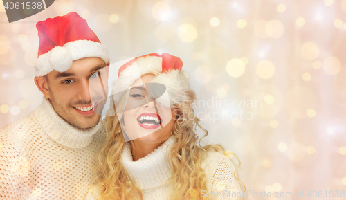 Image of happy family couple in sweaters and santa hats