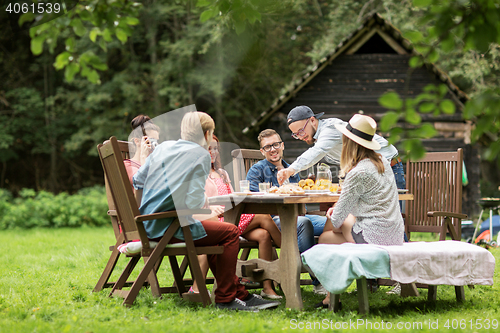 Image of happy friends having dinner at summer garden party