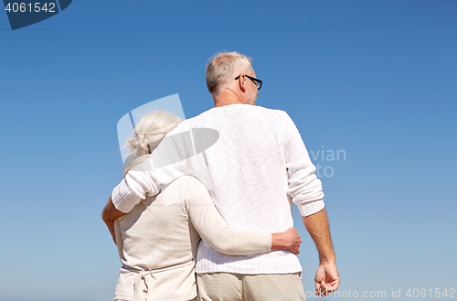 Image of happy senior couple hugging on summer beach