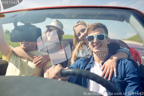 Image of happy friends driving in cabriolet car outdoors