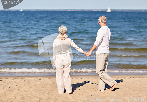 Image of happy senior couple holding hands summer beach
