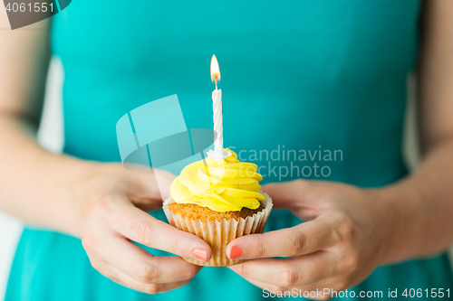Image of woman with burning candle on birthday cupcake