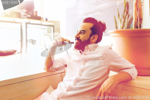 Image of smiling man with beard and hair bun at office