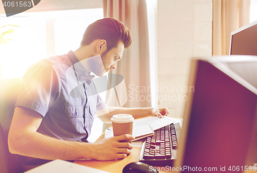 Image of creative male worker drinking coffee and reading